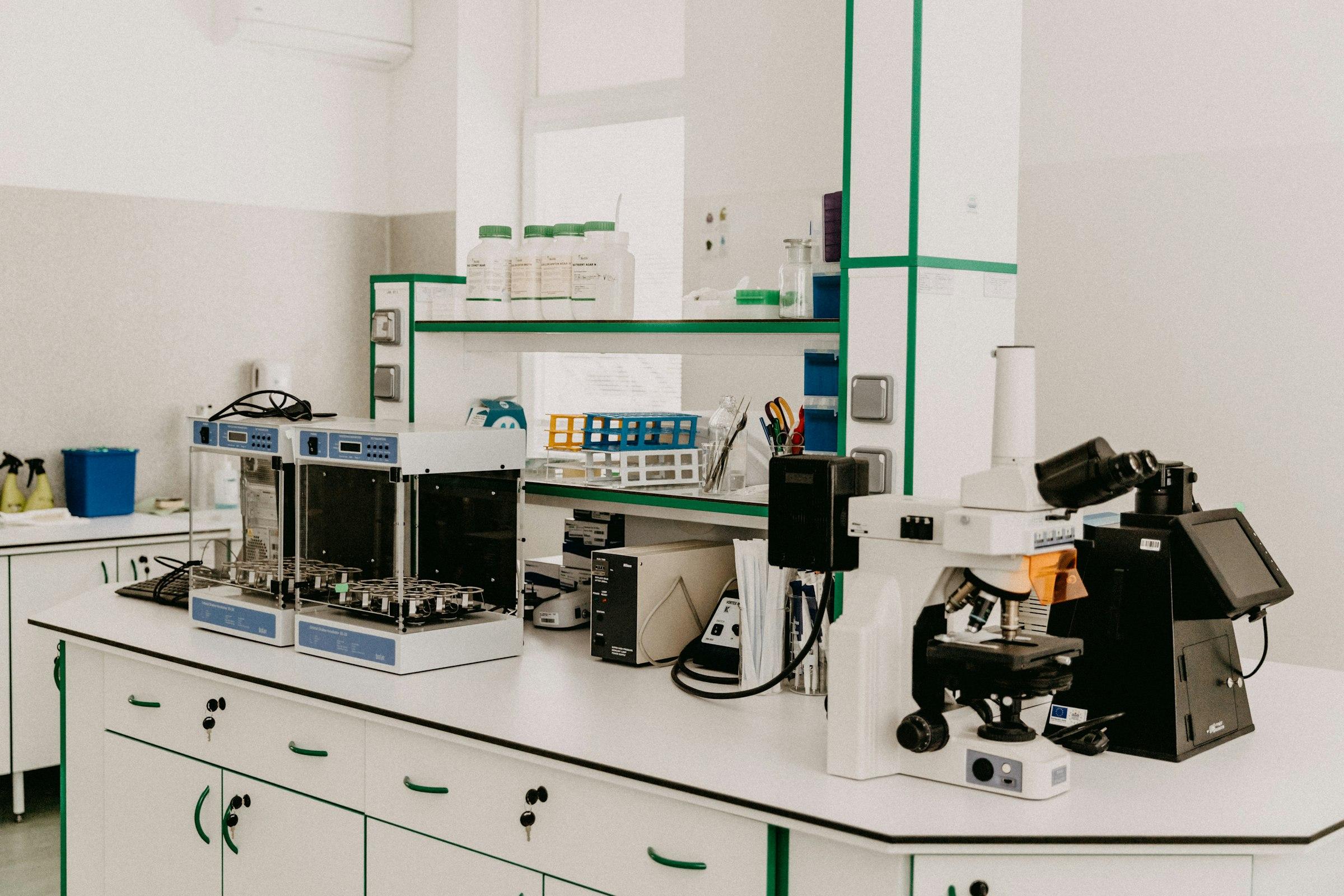 Laboratory workbench with microscopes and analytical instruments.